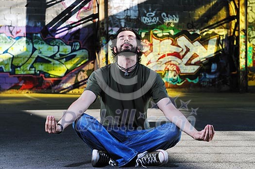young happy man in urban enviroment practicing and meditating yoga in lotus position young happy man in urban enviroment practicing and meditating yoga in lotus position