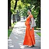 beautiful young happy pregnant woman outdoor in bright nature in orange dress