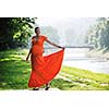beautiful young happy pregnant woman outdoor in bright nature in orange dress