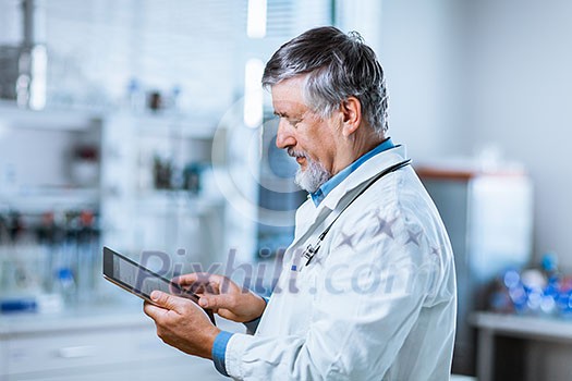Senior doctor using his tablet computer at work (color toned image) Senior doctor using his tablet computer at work (color toned image)