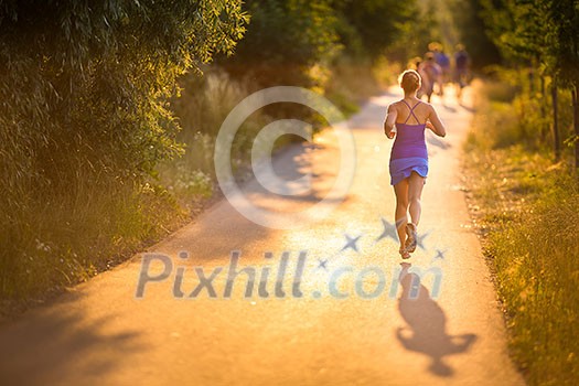 Young woman running outdoors on a lovely sunny summer evening (shallow DOF; color toned image) Young woman running outdoors on a lovely sunny summer evening (shallow DOF; color toned image)