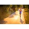 Young woman running outdoors on a lovely sunny summer evening (shallow DOF; color toned image)