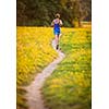 Young woman running outdoors on a lovely sunny summer evening (shallow DOF; color toned image)