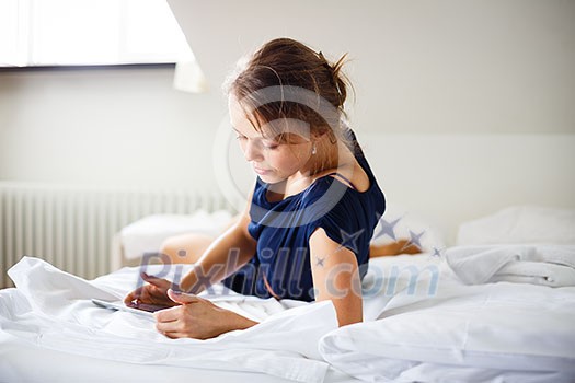 Elegant, smart, young woman using her tablet computer in bed (shallow DOF; color toned image) Elegant, smart, young woman using her tablet computer in bed (shallow DOF; color toned image)