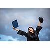 Pretty, young woman celebrating joyfully her graduation - spreading wide her arms, holding her diploma, savouring her success (color toned image; shallow DOF)