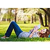 Young woman using her tablet computer while relaxing outdoors in a park on a lovely spring day