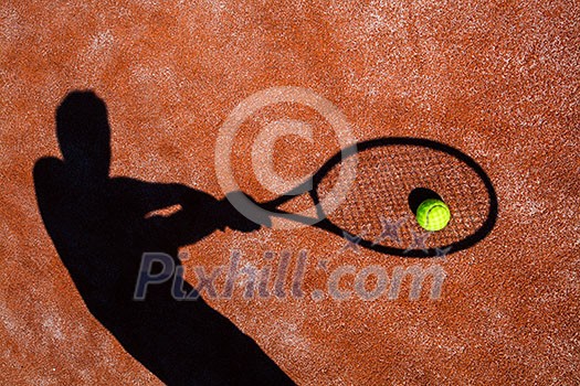 shadow of a tennis player in action on a tennis court (conceptual image with a tennis ball lying on the court and the shadow of the player positioned in a way he seems to be playing it) shadow of a tennis player in action on a tennis court (conceptual image with a tennis ball lying on the court and the shadow of the player positioned in a way he seems to be playing it)