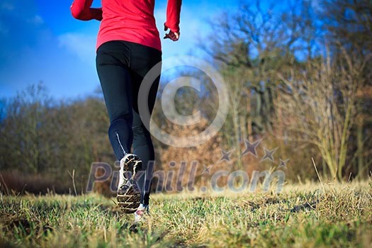 Jogging outdoors in a meadow (shallow dof, focus on the running shoe)