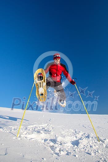 Young man having fun while snowshoeing outdoors on a lovely snowy winter day Young man having fun while snowshoeing outdoors on a lovely snowy winter day