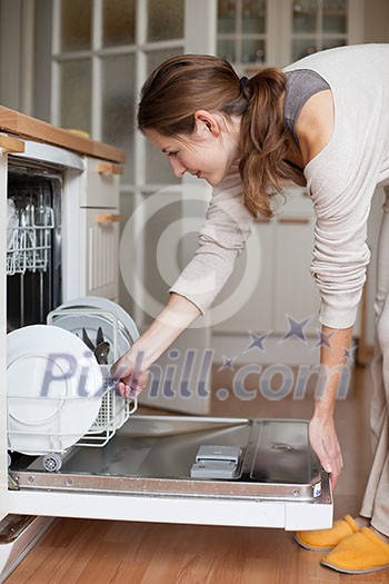 Housework: young woman putting dishes in the dishwasher Housework: young woman putting dishes in the dishwasher