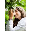 Beautiful young woman smelling white jasmin flowers