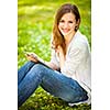 Young woman using her tablet computer while relaxing outdoors in a park on a lovely spring day