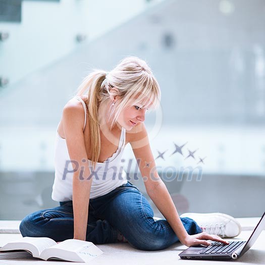 On campus - pretty female student with laptop and books working before class on her assignment/homework (color toned image) On campus - pretty female student with laptop and books working before class on her assignment/homework (color toned image)