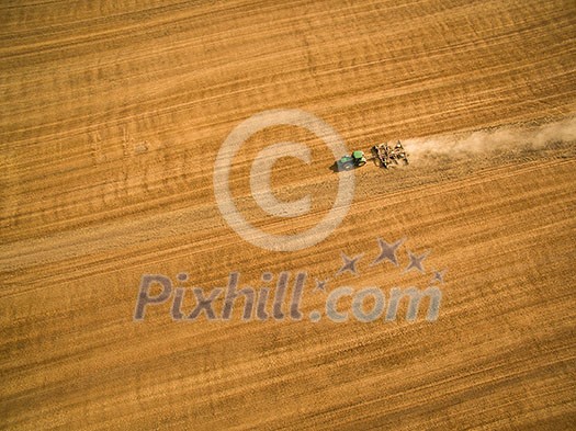 Aerial view of a tractor working a field after harvest Aerial view of a tractor working a field after harvest
