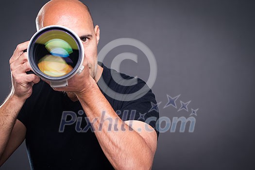 Young, pro male photographer in his studio during a photo shoot (color toned image; shallow DOF)