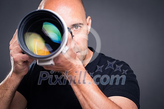 Young, pro male photographer in his studio during a photo shoot (color toned image; shallow DOF) Young, pro male photographer in his studio during a photo shoot (color toned image; shallow DOF)