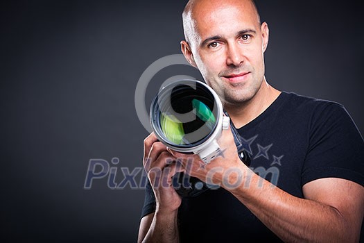 Young, pro male photographer in his studio during a photo shoot (color toned image; shallow DOF)
