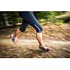 Young woman running outdoors in a forest, going fast (motion blurred image)