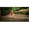 Young woman running outdoors in a forest, going fast (motion blurred image)