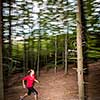 Young woman running outdoors in a forest, going fast (motion blurred image)