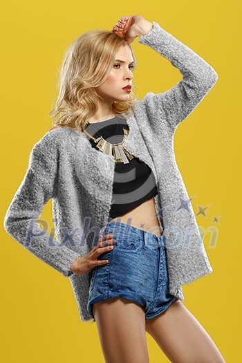 Beautiful blond model in shorts and a t-shirt on a yellow background Beautiful blond model in shorts and a t-shirt on a yellow background