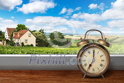 View of house on summer vineyard landscape from window with alarm clock View of house on summer vineyard landscape from window with alarm clock