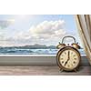 View of summer sea under blue sky from window with alarm clock