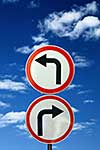 two opposite road signs against blue sky and clouds