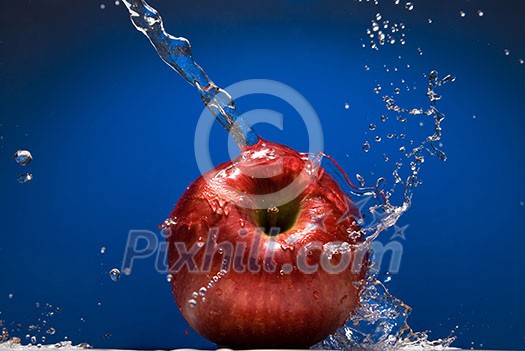Red apple with water splash on blue background Red apple with water splash on blue background