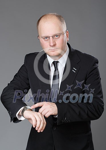 Businessman look his watch, isolated on a grey background Businessman look his watch, isolated on a grey background