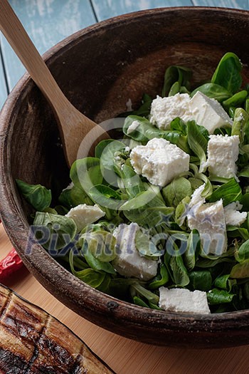 Salad of fresh greens and feta cheese in a wooden bowl Salad of fresh greens and feta cheese in a wooden bowl