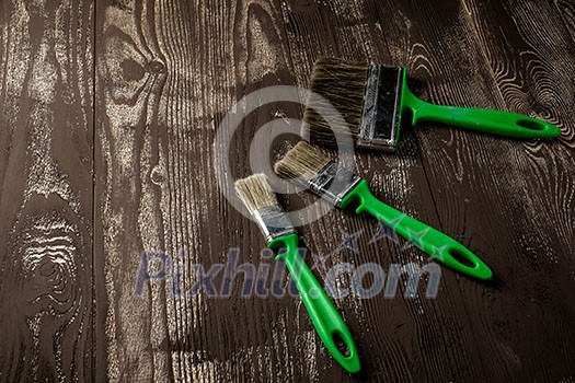 Three brushes for painting on a dark wooden table Three brushes for painting on a dark wooden table