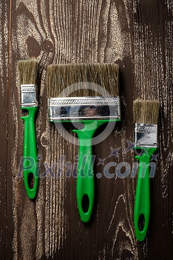 Three brushes for painting on a dark wooden table Three brushes for painting on a dark wooden table