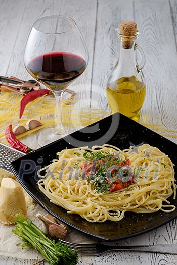 Italian pasta cooked in a rustic style with a sauce of fresh tomatoes and garlic on a wooden table with a glass of red wine. Italian pasta cooked in a rustic style with a sauce of fresh tomatoes and garlic on a wooden table with a glass of red wine.