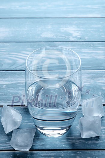 Glass of water and melting ice cubes on a wooden table Glass of water and melting ice cubes on a wooden table
