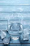 Glass of water and melting ice cubes on a wooden table