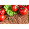 red tomatoes with green salad on wood