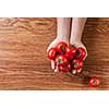 red tomatoes in hands on wooden background
