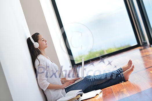 beautiful young woman relax and work on laptop computer while listening music on heaphones and read book at home beautiful young woman relax and work on laptop computer while listening music on heaphones and read book at home