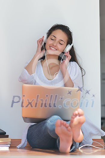 beautiful young woman relax and work on laptop computer while listening music on heaphones and read book at home beautiful young woman relax and work on laptop computer while listening music on heaphones and read book at home