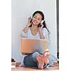 beautiful young woman relax and work on laptop computer while listening music on heaphones and read book at home