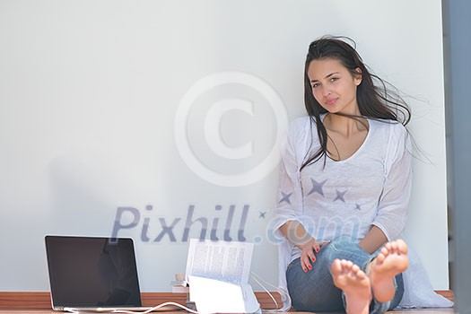 beautiful young woman relax and work on laptop computer while listening music on heaphones and read book at home beautiful young woman relax and work on laptop computer while listening music on heaphones and read book at home