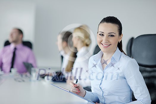 Successful business woman standing with her staff in background at modern bright office Successful business woman standing with her staff in background at modern bright office