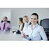 Successful business woman standing with her staff in background at modern bright office