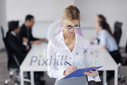Successful business woman standing with her staff in background at modern bright office Successful business woman standing with her staff in background at modern bright office