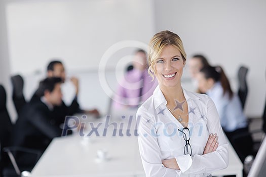 Successful business woman standing with her staff in background at modern bright office