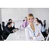 Successful business woman standing with her staff in background at modern bright office