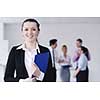 Successful business woman standing with her staff in background at modern bright office