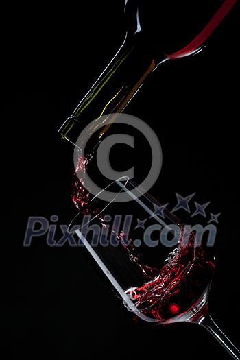 red wine pouring into wine glass isolated on black red wine pouring into wine glass isolated on black