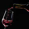 red wine pouring into wine glass isolated on black